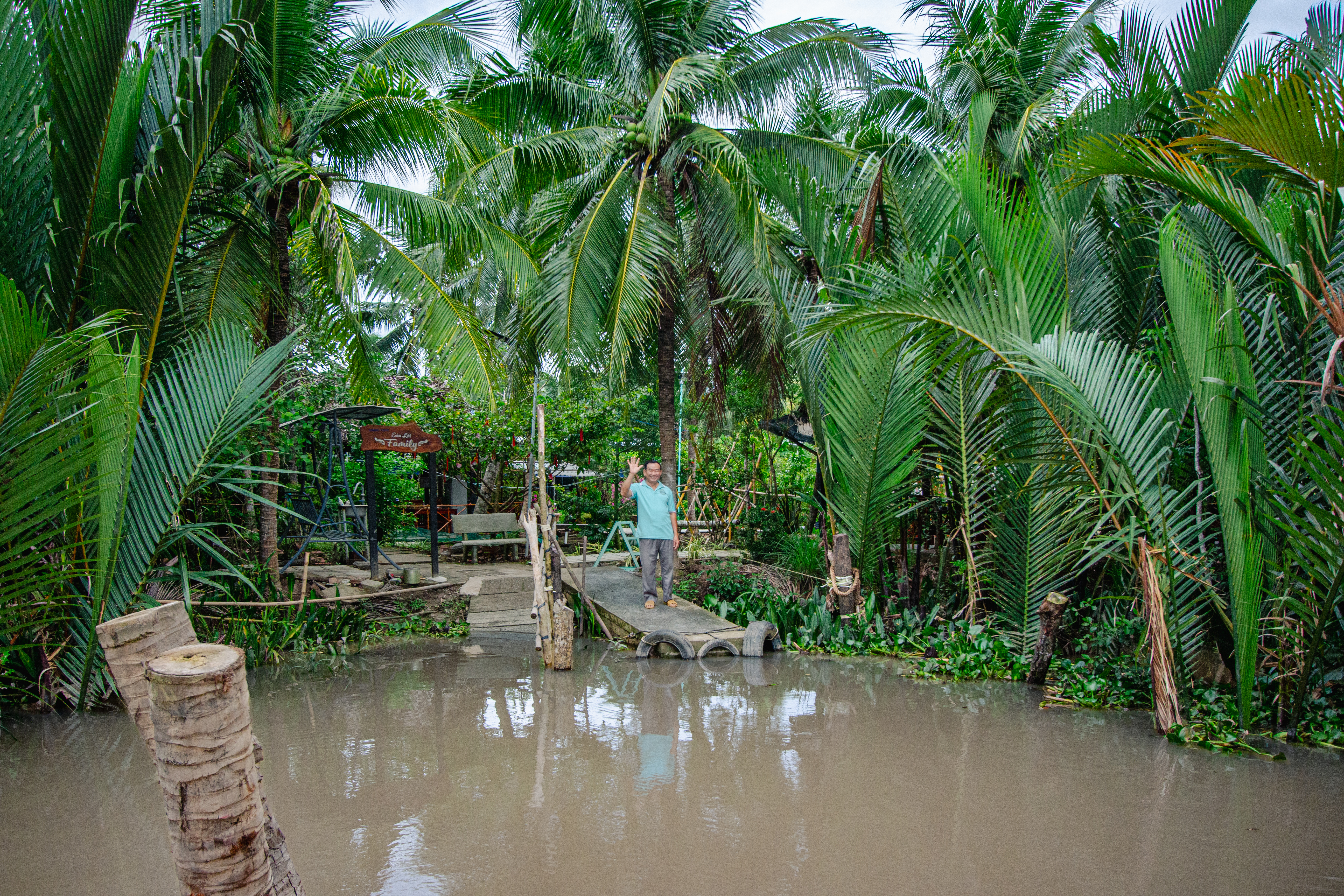 foto di uomo che saluta da un piccolo porticciolo sul fiume mekong